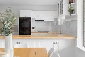 a kitchen with white cabinets and a wooden counter top at The Arches ~ Style, location and spacious living! in McLaren Vale