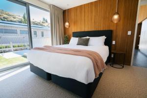 um quarto com uma cama grande e uma janela grande em Abodo Alpine Eco Villa (Spa) em Cardrona