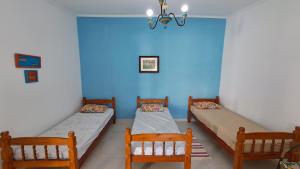 two beds in a room with a blue wall at Suíte Beach Host - Praia Pernambuco in Guarujá