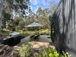 a patio with a table and an umbrella and a grill at Base Glamp Bruny Island in Alonnah