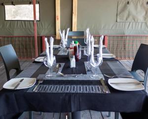 a black table with plates and wine glasses on it at Riverside Lodge in Katima Mulilo