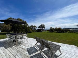 a patio with a table and chairs and an umbrella at Boomers Retreat, Alonnah, Bruny Island in Alonnah