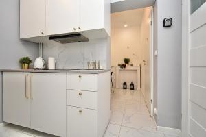 a kitchen with white cabinets and a tile floor at Rental Apartments Aleja Niepodległości in Warsaw