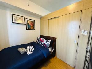 um quarto com uma cama com lençóis e almofadas azuis em 1bedroom With Balcony Taguig Near Bgc mc kinley em Manila