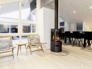 JerupにあるHoliday Home Brattenvejの暖炉付きのリビングルーム(椅子、テーブル付)