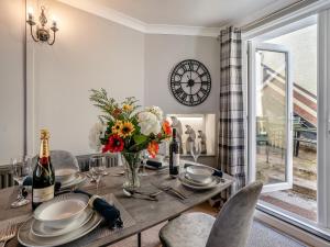 a dining room with a table with flowers and a clock at The Llandeilo Cottage in Llandeilo