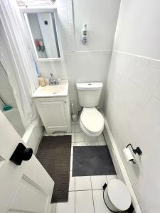 a white bathroom with a toilet and a sink at 6-A Diamond in Yonkers, NY in Yonkers