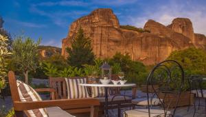 a patio with a table and chairs with mountains in the background at Hotel Doupiani House in Kalabaka