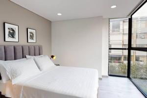 een slaapkamer met een groot wit bed en een raam bij Unicentro North Retreat 2 Rooms in Bogota