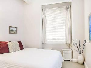 a white bedroom with a bed and a window at Inner City 2 Bedroom Apartment Self Catering in Sydney