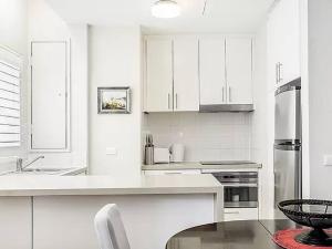 a white kitchen with a sink and a refrigerator at Inner City 2 Bedroom Apartment Self Catering in Sydney