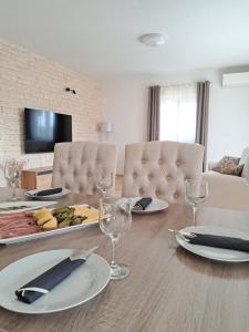 ein Esszimmer mit einem Tisch mit Tellern und Weingläsern in der Unterkunft Family friendly house with a swimming pool Sibenik - 21939 in Šibenik