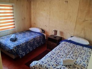 Habitación con 2 camas, mesita de noche y cama doble en Residencial 4 estaciones, en Futaleufú