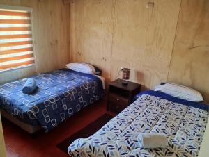 um quarto com 2 camas, uma mesa de cabeceira e uma cama em Residencial 4 estaciones em Futaleufú
