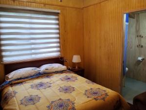 1 dormitorio con 1 cama y ventana en Residencial 4 estaciones, en Futaleufú