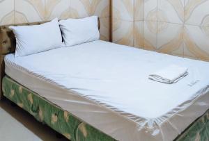 a bed with a white sheets and a pillow at RedDoorz @ PVC Pension Haus in Tagum