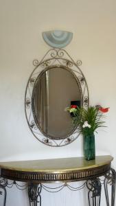 a mirror on top of a table with a vase with flowers at ibis Apartments - Ground Floor - Summersun Residence - Grand Baie, Pereybere in Grand Baie