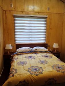 um quarto com uma cama com 2 candeeiros e uma janela em Residencial 4 estaciones em Futaleufú