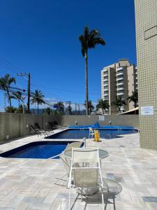 a swimming pool with two chairs and a palm tree at Apto beira mar pé na areia in Caraguatatuba