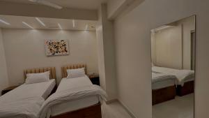 two beds in a room with a mirror at DrizzleDrop Inn Chennai in Chennai