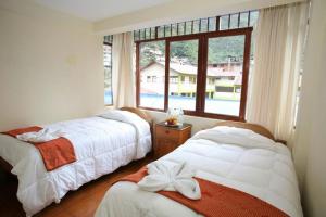 two beds in a room with a window at Hotel Romero Machupicchu in Machu Picchu