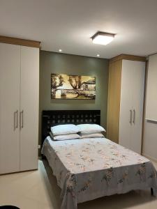 a bedroom with a bed and a painting on the wall at Apto beira mar pé na areia in Caraguatatuba +12 photos