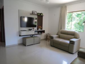 a living room with a couch and a tv on a wall at Recanto do Mundaí - Apto 202 in Porto Seguro