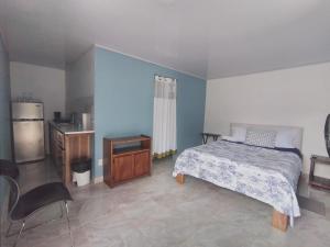 Schlafzimmer mit einem Bett, einem Tisch und einem Kühlschrank in der Unterkunft Villa el paraíso in San José
