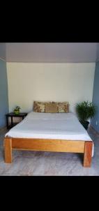 1 cama con marco de madera en un dormitorio en Villa el paraíso, en San José
