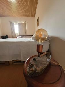 een slaapkamer met een bed en een tafel met een lamp bij EcoviLab in Guaratinguetá
