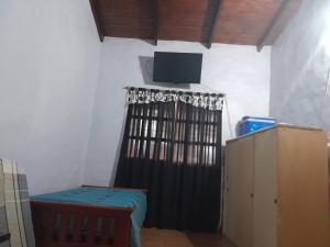 una habitación con cortina negra y TV en la pared en No Reservar en San Vicente