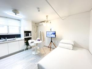 a white bedroom with a bed and a desk at Koin Guesthouse Incheon airport in Incheon