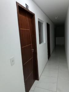 um corredor com uma porta de madeira num quarto em Pousada Canto dos Corais em Maragogi