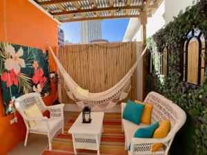 a hammock on a patio with chairs and a table at Tropical Apartments in Miramar in San Juan