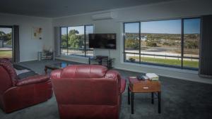 a living room with couches and a tv and windows at Highview on Victoria Coffin Bay in Coffin Bay