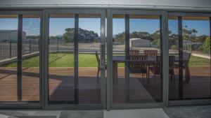 a screened in porch with a table and chairs on a deck at Highview on Victoria Coffin Bay in Coffin Bay