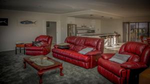 a living room with red leather couches and a table at Highview on Victoria Coffin Bay in Coffin Bay