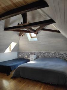 - une chambre avec un grand lit dans une pièce dotée de lucarnes dans l'établissement Agréable maison de village avec jardin., à Beaulieu-sur-Dordogne