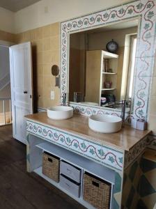 La salle de bains est pourvue de 2 lavabos et d'un grand miroir. dans l'établissement Agréable maison de village avec jardin., à Beaulieu-sur-Dordogne