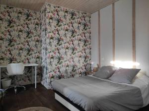 - une chambre avec un lit et un papier peint floral dans l'établissement Agréable maison de village avec jardin., à Beaulieu-sur-Dordogne