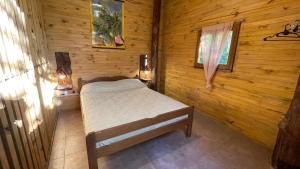 ein Schlafzimmer mit einem Bett in einer Holzhütte in der Unterkunft Casa Barranca del Mbocay in Puerto Iguazú