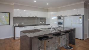 a kitchen with a sink and a counter with stools at Waterfront on Osprey in Coffin Bay