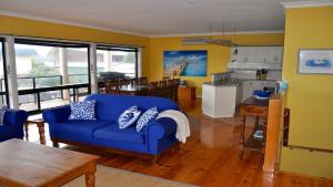 a living room with a blue couch and a kitchen at Coffin Bay Retreat in Coffin Bay
