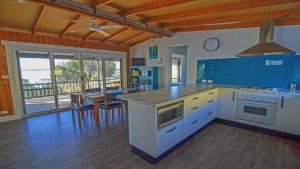 a large kitchen with blue cabinets and a table with chairs at CDC-625 Beach House in Coffin Bay