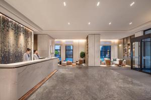 two people standing at a counter in a lobby at Citadines Jinqiao Building Yantai in Yantai