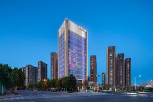a tall building in a city with tall buildings at Citadines Jinqiao Building Yantai in Yantai