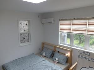 a bedroom with two twin beds and two windows at All In One Guesthouse in Incheon