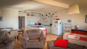 a living room with chairs and a kitchen with a refrigerator at Seascape in Coffin Bay