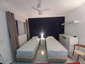 Habitación pequeña con 2 camas y mesa. en Suíte Studio 1 Enseada Tortuga Mobiliada, en Guarujá