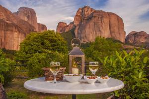 a table with two glasses of wine on it with mountains at Hotel Doupiani House in Kalabaka